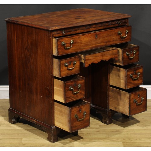 1228 - A George III mahogany kneehole desk, the ovolu moulded top above a brushing slide, axe head handles,... 