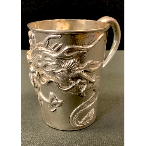 384 - A Chinese silver cup possibly by Wang Hing, the sides finely relief decorated with a dragon on scale... 