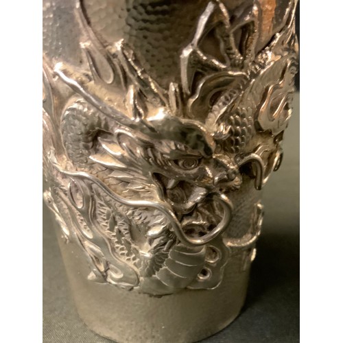 384 - A Chinese silver cup possibly by Wang Hing, the sides finely relief decorated with a dragon on scale... 