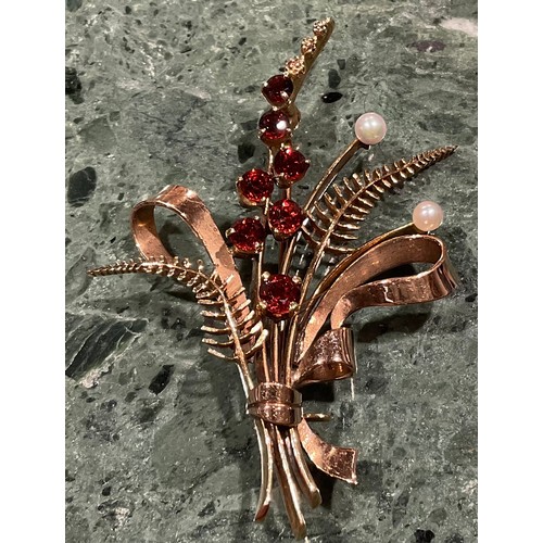 943 - A 9ct gold garnet and seed pearl brooch, cast as a spray of ribbon tied ferns and budding stems, the... 