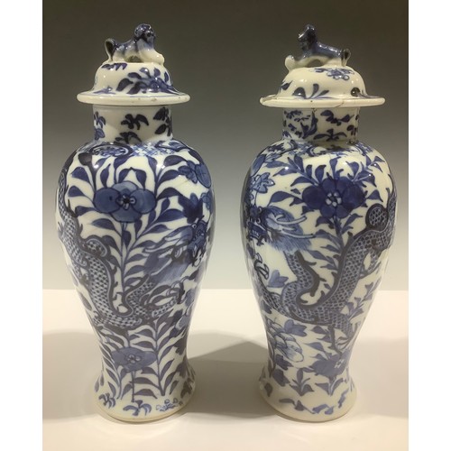 5098 - A near pair of Chinese baluster vases and covers, painted in tones of underglaze blue with dragons a... 