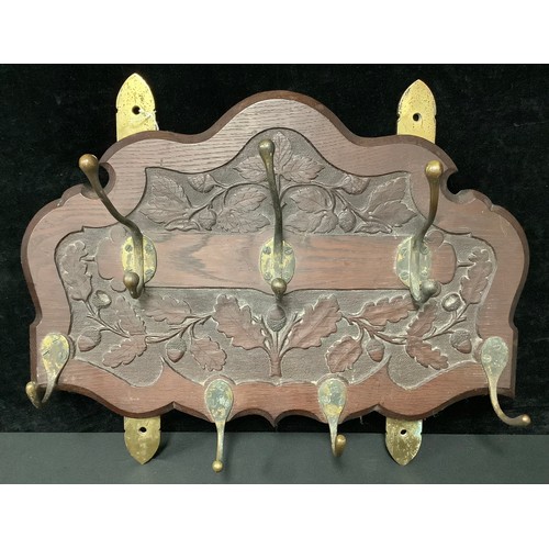 5389 - An oak Arts and Crafts shield shaped hall rack, carved with spreading leafy oak and acorn motifs, wi... 