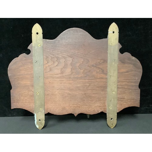 5389 - An oak Arts and Crafts shield shaped hall rack, carved with spreading leafy oak and acorn motifs, wi... 