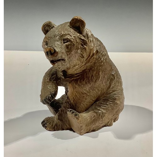 5471 - A Black Forest carved bear, seated with paw raised, 12cm