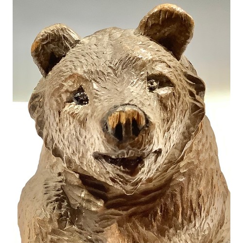 5471 - A Black Forest carved bear, seated with paw raised, 12cm