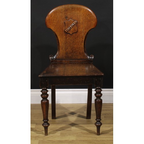 1543A - A Victorian oak hall chair, shaped back carved and applied with a shield, turned forelegs, 86cm high... 