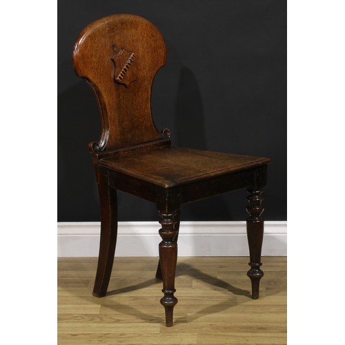 1543A - A Victorian oak hall chair, shaped back carved and applied with a shield, turned forelegs, 86cm high... 