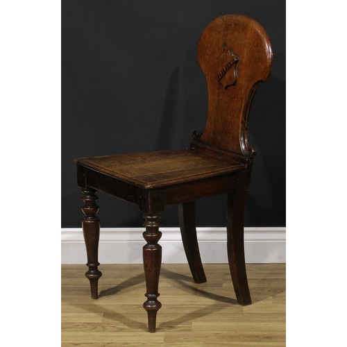 1543A - A Victorian oak hall chair, shaped back carved and applied with a shield, turned forelegs, 86cm high... 