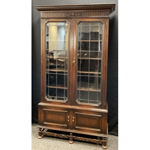 52 - An early 20th century oak bookcase cabinet, outswept cornice, pair of glazed leaded doors enclosing ... 