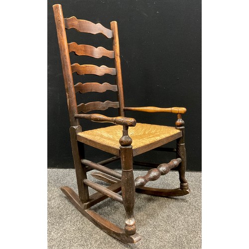 204 - A George III elm ladder-back rocking chair, of small proportions, rush seat, 95.5cm high x 51cm wide... 