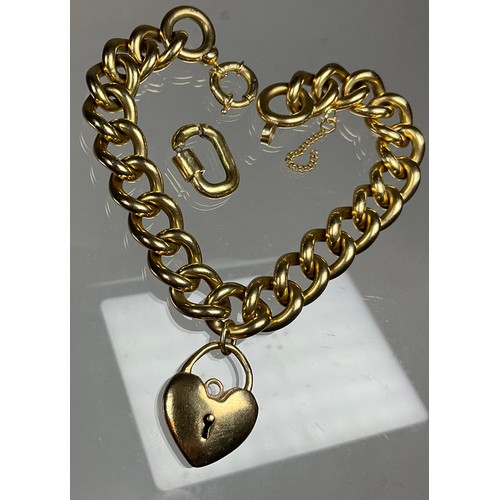 308 - A heavy solid link yellow metal twist link bracelet, 23cm long, 1cm wide, suspending a heart padlock... 