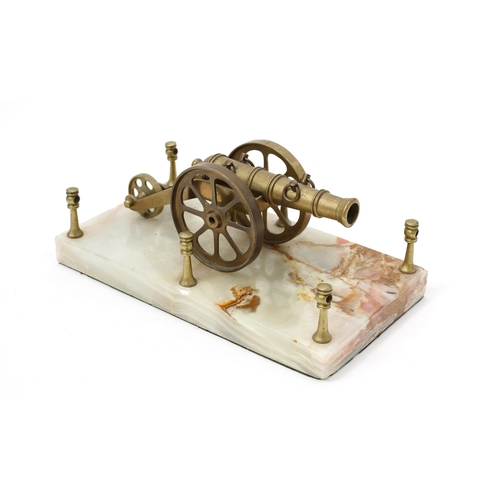 83 - A brass desk model of a cannon, mounted on a rectangular shaped onyx base, 23cm wide