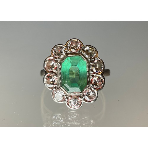 296 - An emerald and diamond cluster ring, central step cut mid tone emerald, approx 9mm x 7mm x 5mm, esti... 