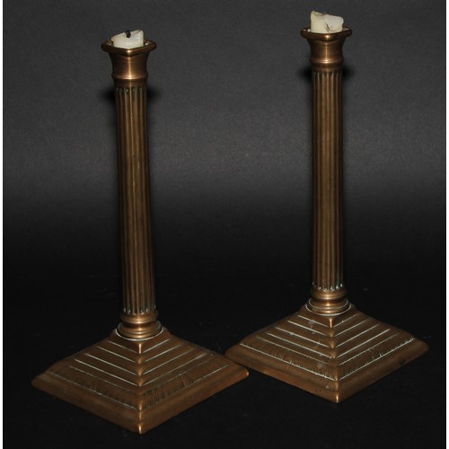 302 - A pair of George III brass fluted square candlesticks, of seamed construction, stepped square bases ... 