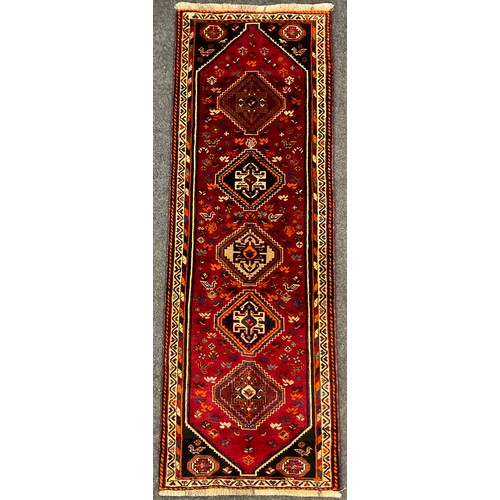 65 - A South West Persian Qashgai runner carpet, hand-knotted in rich tones of red, black, blue, and oran... 