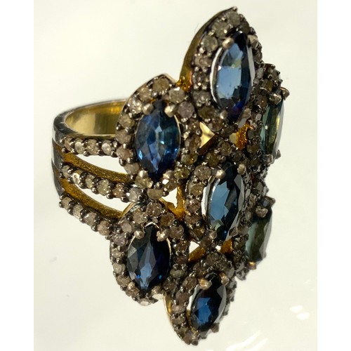 369 - An Edwardian style diamond and sapphire multi panel cluster ring, composed of seven navette clusters... 