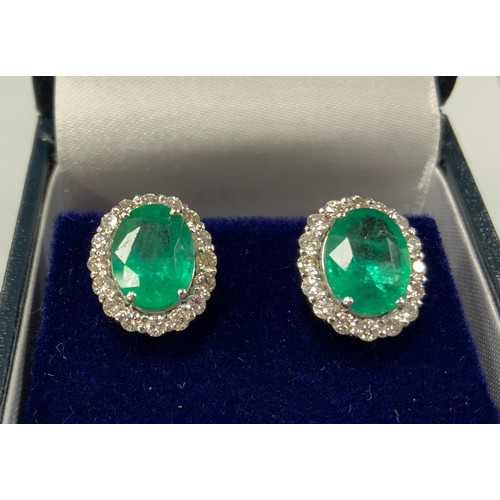 370 - A pair of emerald and diamond cluster earrings, each with a central oval emerald surrounded by eight... 