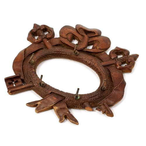 3062 - A Black Forest wall-hanging key hook, carved with triumphal regalia, 18cm wide, c.1900