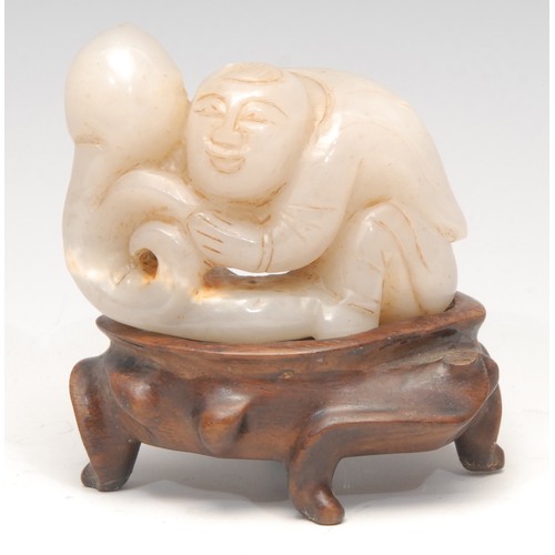 3071 - A Chinese jade carving, of a figure holding a peach, 6.5cm wide, hardwood stand