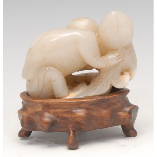 3071 - A Chinese jade carving, of a figure holding a peach, 6.5cm wide, hardwood stand