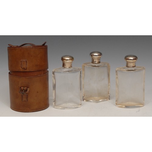 3168 - A set of three Edwardian silver mounted glass cologne bottles, leather cylindrical case, 14.5cm high... 