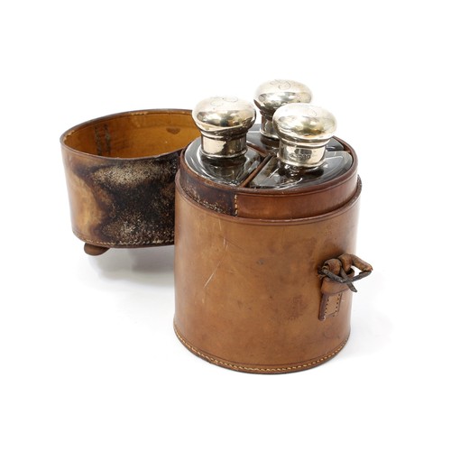 3168 - A set of three Edwardian silver mounted glass cologne bottles, leather cylindrical case, 14.5cm high... 