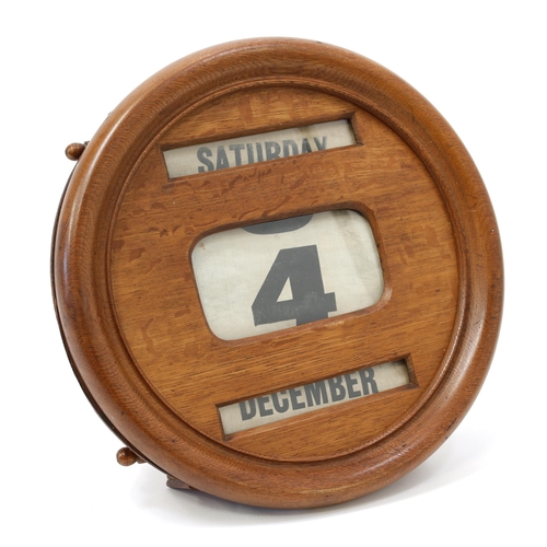 3214 - An early 20th century oak wall mounted perpetual calendar, glazed apertures for day, date and month,... 