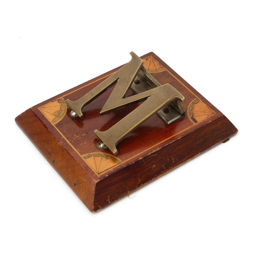 3222 - An Edwardian mahogany and brass novelty letter clip, as a letter M, the spreading rectangular base i... 