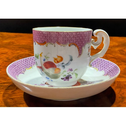 125 - A Meissen coffee cup and saucer, painted with ripening fruit and nuts, under a puce scale border, gi... 