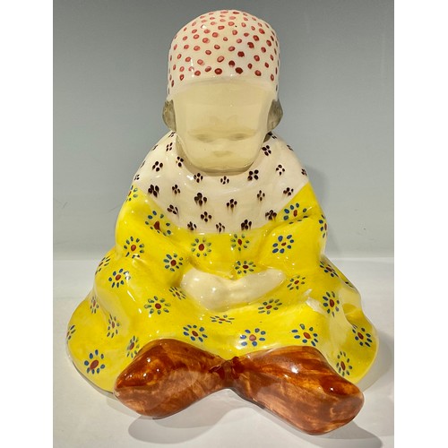 139 - A Berthe Savigny Quimper figure, modelled as a seated child, wearing a bonnet, a nightdress, and clo... 