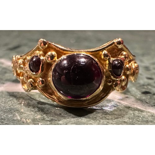 307 - An 18ct gold garnet ring, set with three oval and circular cabochon red garnets, shaped scrolling cr... 