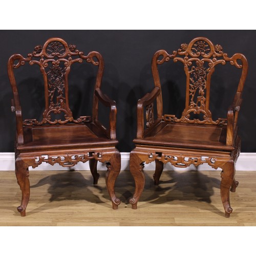 191 - A pair of Chinese hardwood armchairs, each with a shaped back pierced and carved with scrolls and fl... 