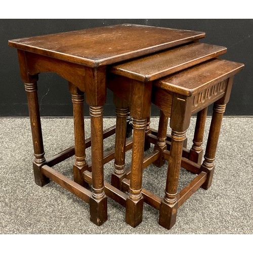 82 - An Old Charm style nest of three oak tables, the largest measuring 53.5cm high x 58.5cm x 38.5cm.