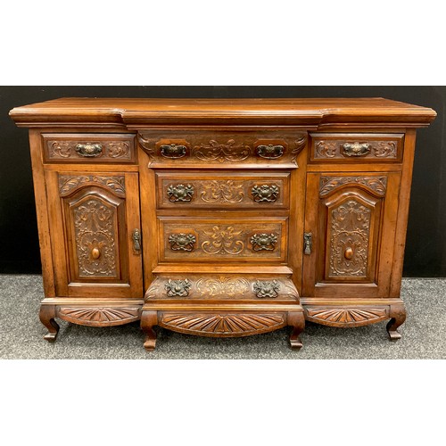 86 - An early 20th century carved walnut sideboard, break-front centred top and base, carved in relief to... 