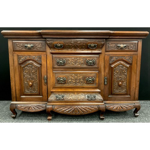 86 - An early 20th century carved walnut sideboard, break-front centred top and base, carved in relief to... 