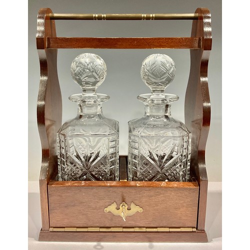 80 - An oak two bottle tantalus, containing rectangular cut glass decanters, 35.5cm