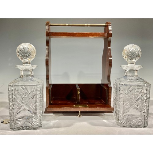 80 - An oak two bottle tantalus, containing rectangular cut glass decanters, 35.5cm