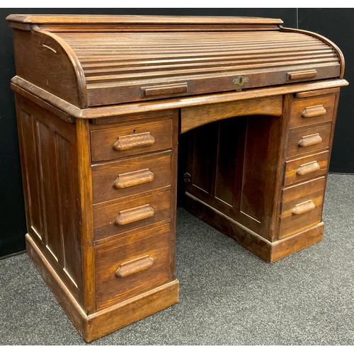 81 - An early to mid 20th century oak roll-top desk, the tambour roll-top enclosing a fitted interior, ab... 