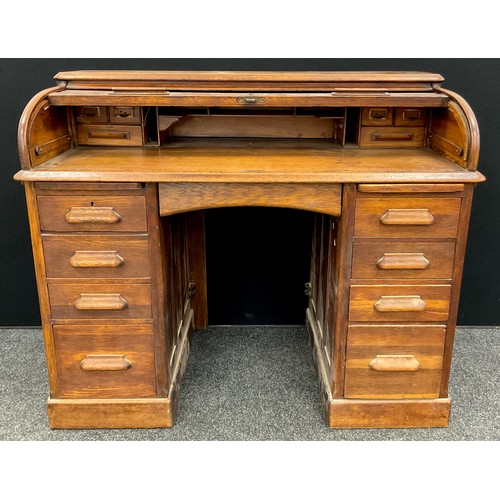 81 - An early to mid 20th century oak roll-top desk, the tambour roll-top enclosing a fitted interior, ab... 