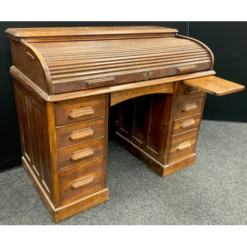 81 - An early to mid 20th century oak roll-top desk, the tambour roll-top enclosing a fitted interior, ab... 