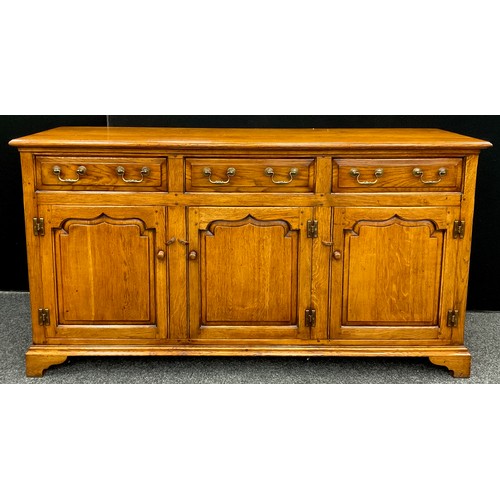 196 - A Titchmarsh and Goodwin style oak dresser base, three short drawers to frieze, over three cupboard ... 