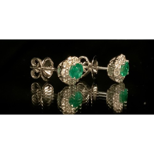 310 - A pair of oval emerald and diamond earrings, central mixed cut emerald within round brilliant cut di... 