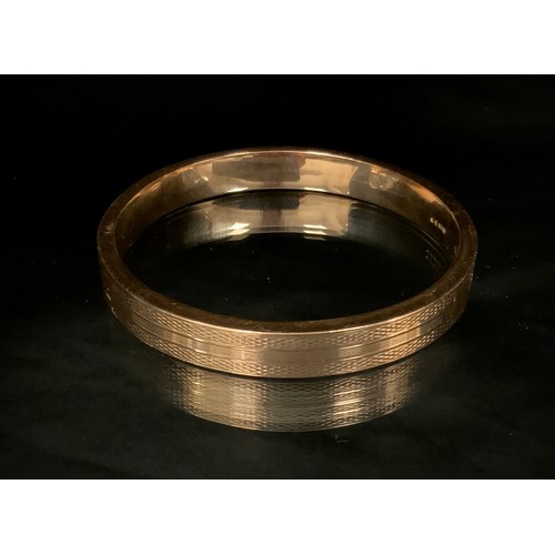 320 - A 9ct gold hollow textured and line banded bangle, import marks, London 1925, 19.3g