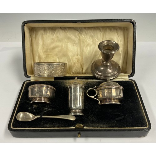 125 - A silver three piece cruet set; a silver candlestick; a silver bangle