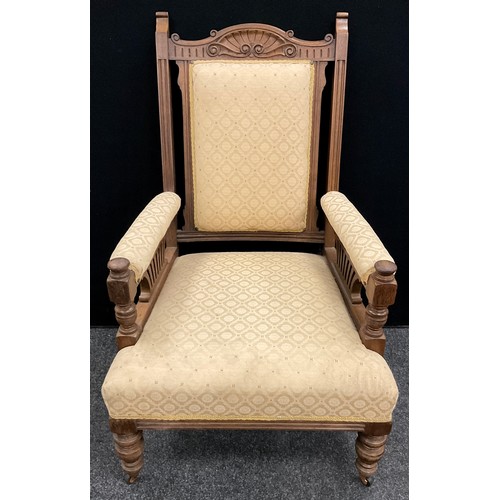 54 - A Victorian walnut library armchair, carved top rail, upholstered back, arms, and seat, turned legs,... 