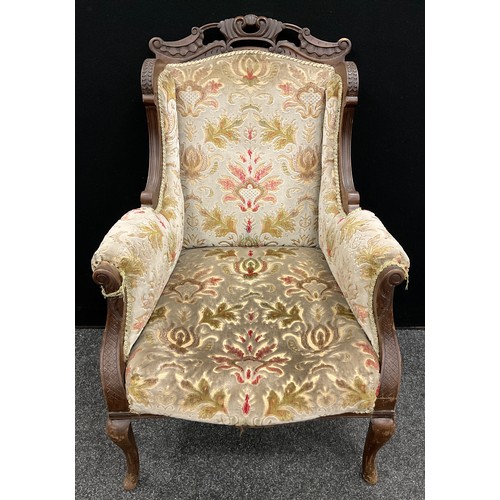 64 - A Victorian carved walnut ‘Chinoiserie’ style wing-back armchair, carved top rail, scroll arms, cabr... 