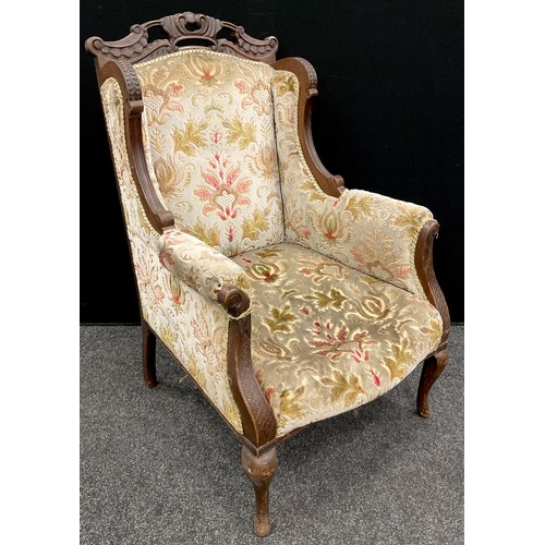 64 - A Victorian carved walnut ‘Chinoiserie’ style wing-back armchair, carved top rail, scroll arms, cabr... 