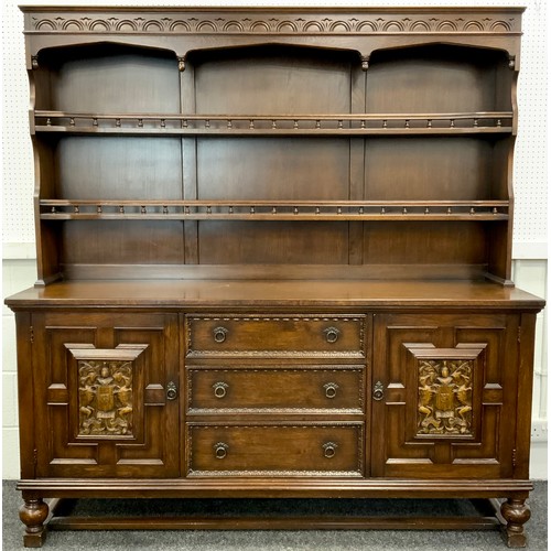 76 - An oak dresser, plate rack top with two tiers of shelving, over a base with pair of carved panel doo... 