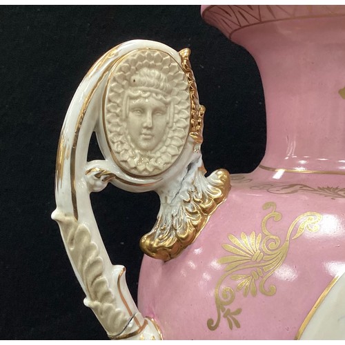 212 - A pair of Sevres style pink cherub vases, twin handled, decorated with printed cherubs on pink groun... 