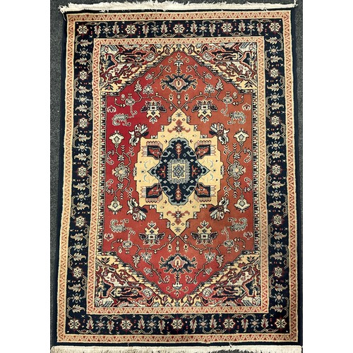 150 - A Middle Eastern style wool rug / carpet, knotted with a central medallion within a field of stylise... 